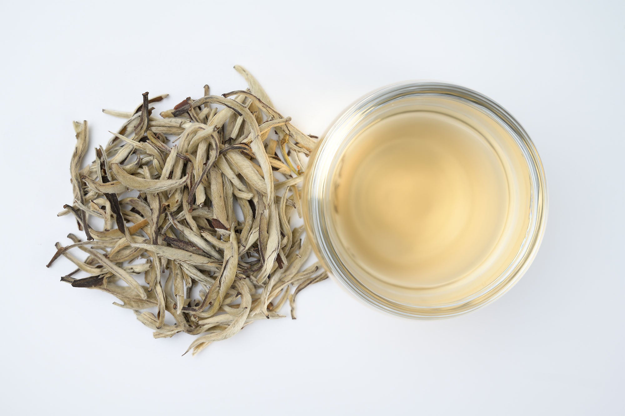 Pale gold tea beside dry leaves